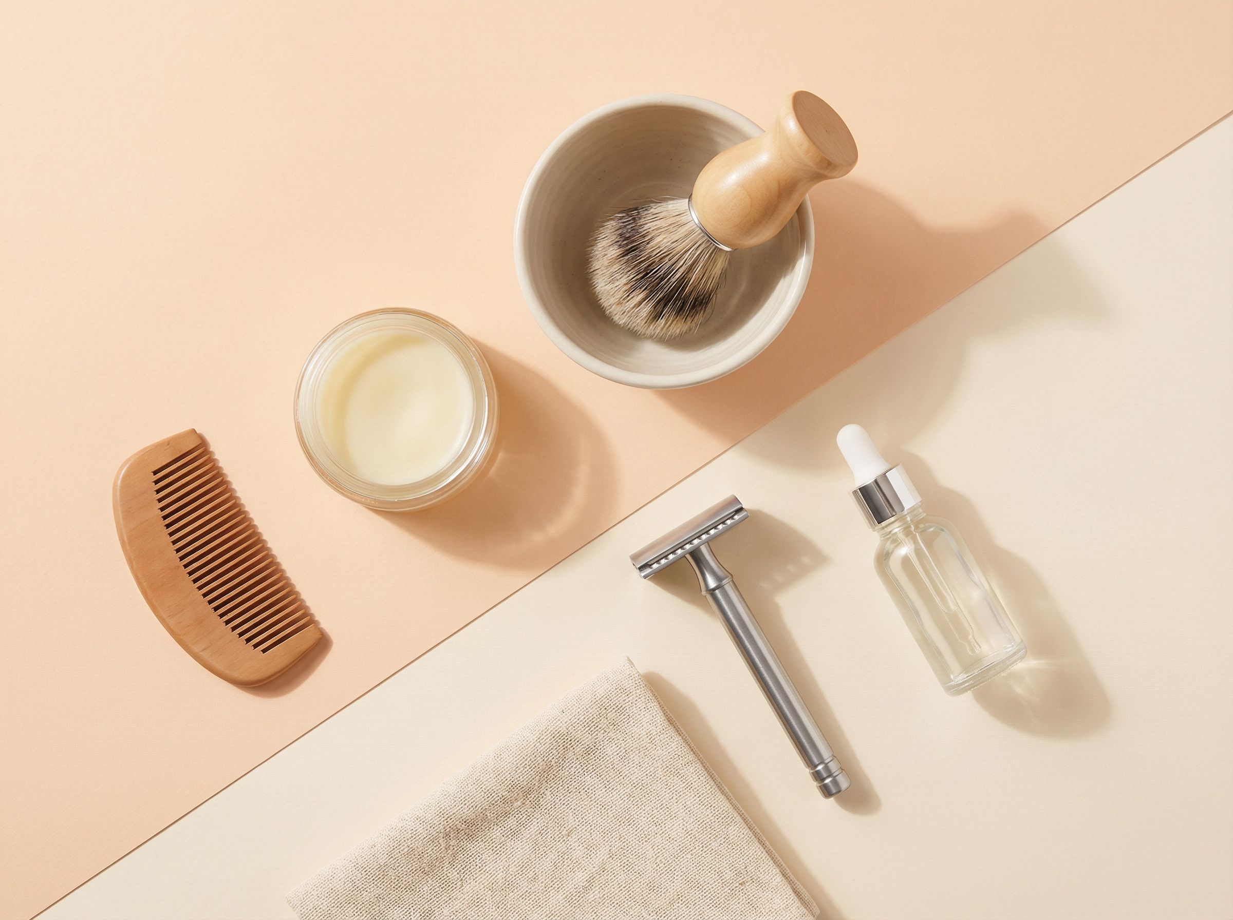 Flat lay of mens grooming essentials on wooden surface, including razor, cream, and comb.